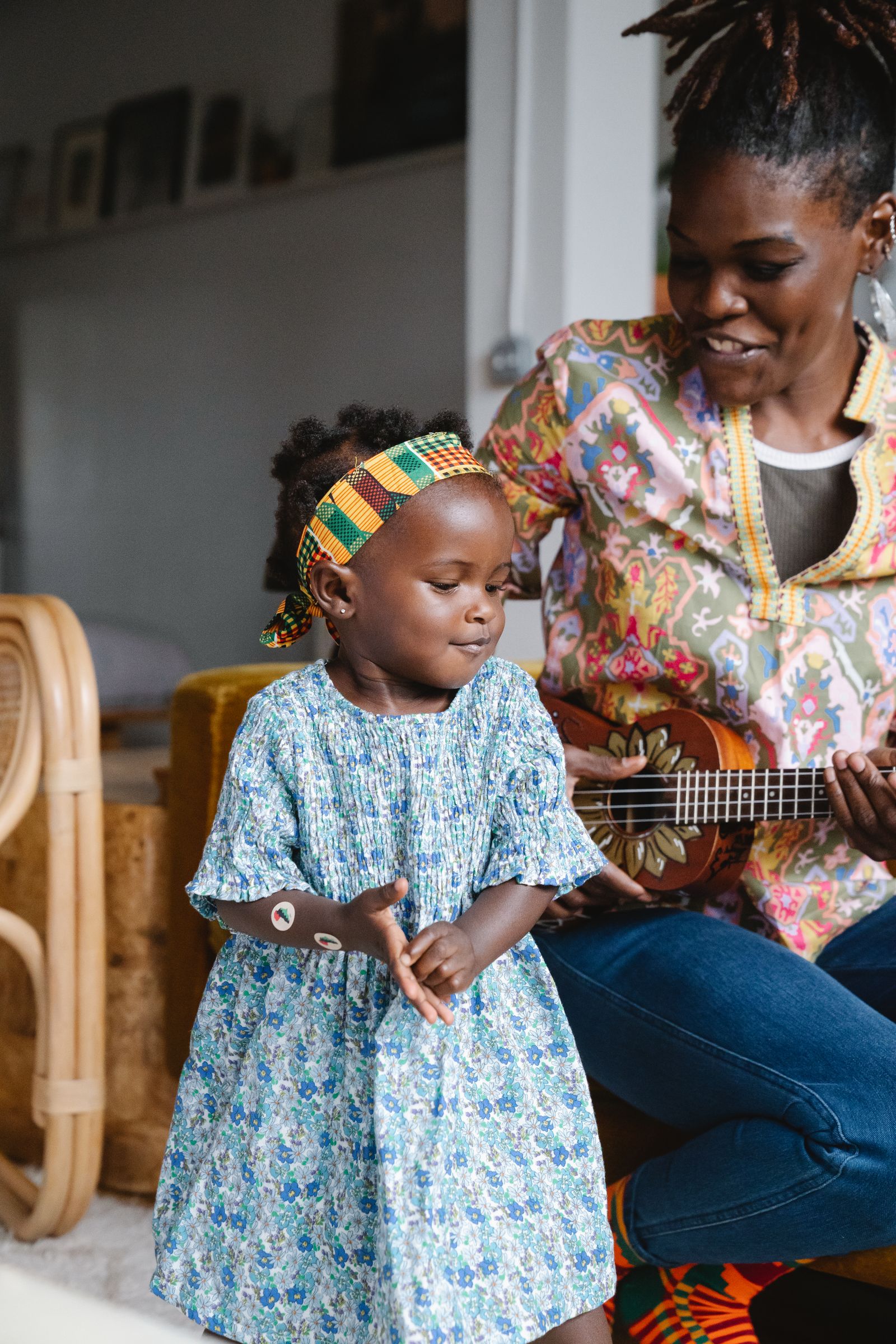 A toddler clapping along as a caregiver plays ukulele