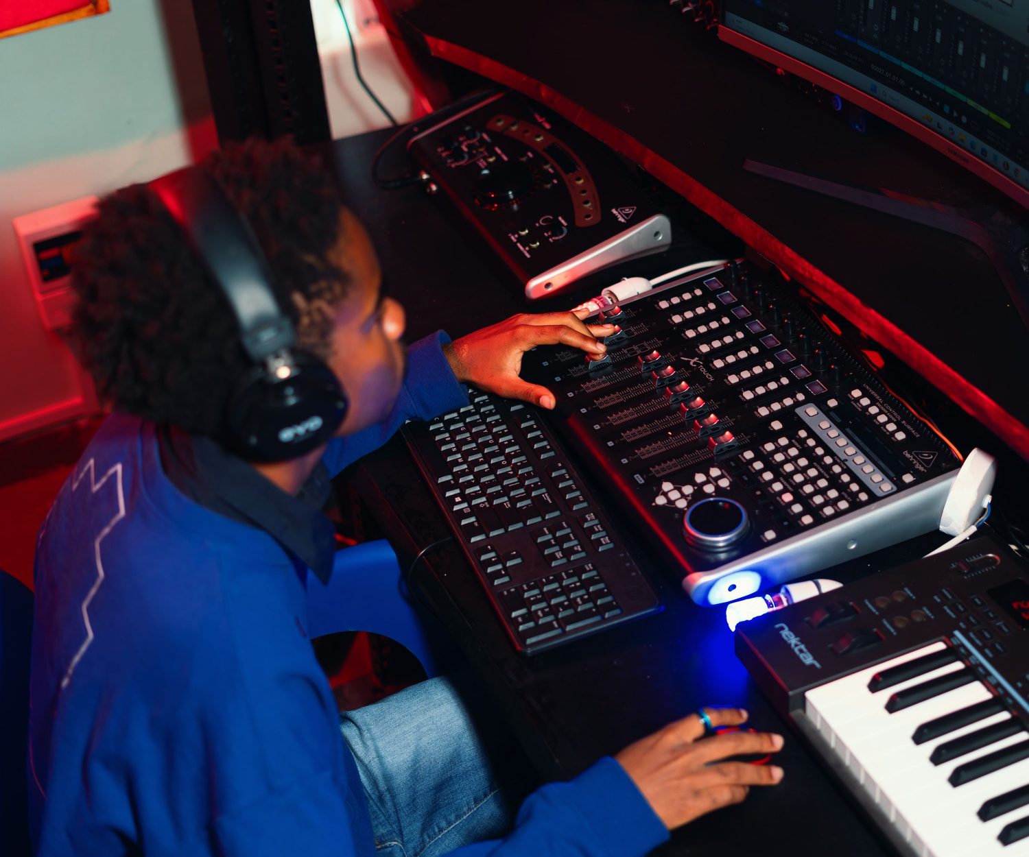 A teenage producer at a mixing desk and keyboard