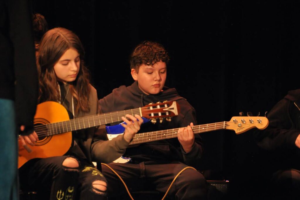 Rockstar instructors and student musicians at a community showcase